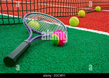 Ball and tennis racket arranged around the net on a synthetic field. Stock Photo