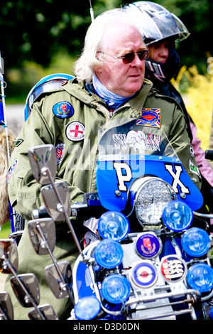 A mature, older,man dressed in 60s mod clothing sitting on a motor scooter Stock Photo