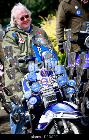 A mature man dressed in mod clothing sitting on a motor scooter Stock Photo