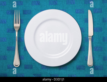 round white plate, knife and fork on table Stock Photo