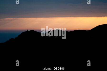 Gower Peninsula, Wales, UK. 16th February 2013. Walkers watching the golden sunset over the Gower Peninsula from the top of Langland Bay Golf Course near Swansea this evening. Credit: Phil Rees/Alamy Live News Stock Photo