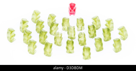 Red Gummi Bear in front of green Gummi Bears (isolated on white) Stock Photo