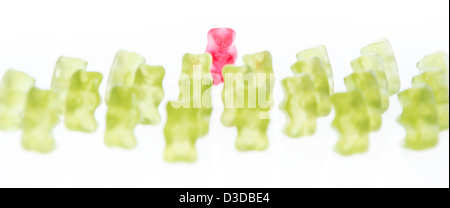 Red Gummi Bear in front of green Gummi Bears (isolated on white) Stock Photo