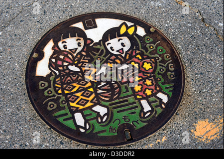 Colorful artistic manhole cover showing two girls in kimono playing with traditional temari threaded balls in Matsumoto, Japan
