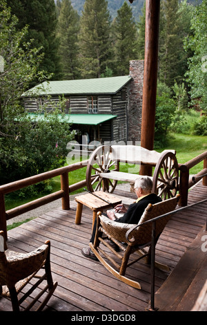 Elderly man sits in rocking chair on veranda of ranch in Montana, USA Stock Photo