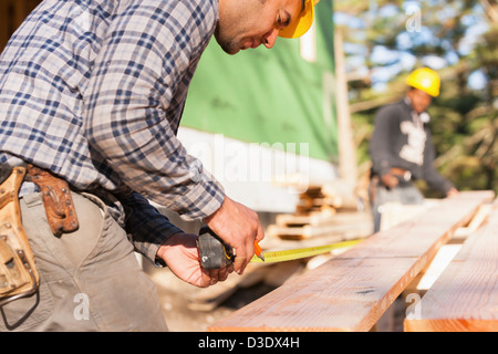 Carpenters measuring a joist in house construction Stock Photo