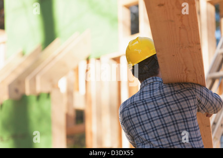 Carpenter carrying a rafter for house under construction Stock Photo