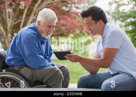 Engineer with muscular dystrophy and diabetes in his wheelchair talking with design engineer using tablet Stock Photo