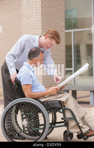 Design engineers reading Plans, one with a spinal cord injury Stock Photo