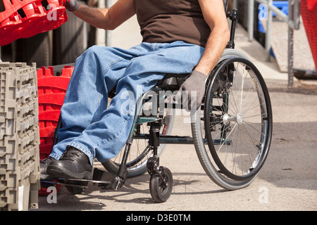 Loading dock worker with spinal cord injury in a wheelchair stacking inventory trays Stock Photo