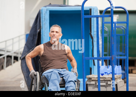 Loading dock worker with spinal cord injury in a wheelchair in storage area Stock Photo