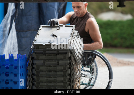 Loading dock worker with spinal cord injury in a wheelchair moving stacked inventory trays Stock Photo