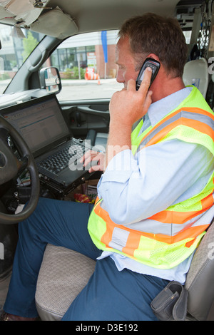Engineer entering data about public water samples on computer in truck Stock Photo