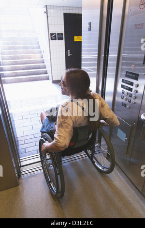 Woman with spinal cord injury in a wheelchair using elevator to train access, Boston, Massachusetts, USA Stock Photo