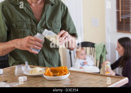 Father preparing baby's formula and mother feeding baby Stock Photo