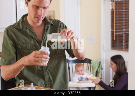 Father preparing baby's formula and mother feeding baby Stock Photo