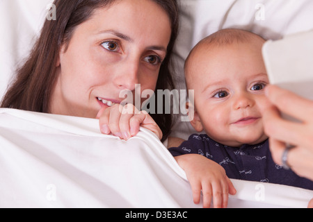 Close-up of a man's hand showing smartphone to his wife and his baby Stock Photo