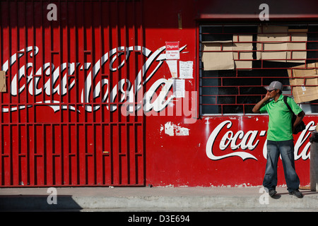 Man talking on cell phone in front of Coca Cola advertisement on a storefront, El Valle, Panama Stock Photo