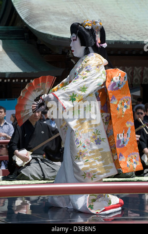 Man dressed in woman's kimono with wig holding folding fan performs traditional dance called Hogaku at Meiji Jingu shrine, Tokyo Stock Photo