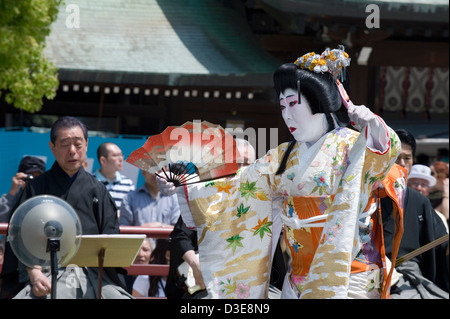 Man dressed in woman's kimono with wig holding folding fan performs traditional dance called Hogaku at Meiji Jingu shrine, Tokyo Stock Photo