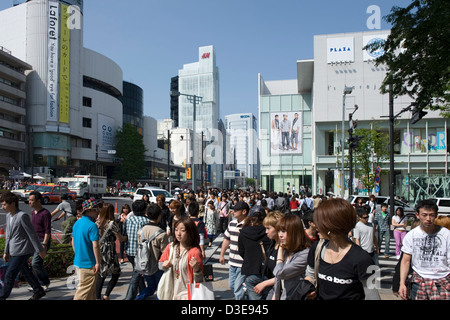 Young shoppers crowd upscale Shibuya district at intersection of Omotesando-dori and Meiji-dori streets on sunny day in Tokyo. Stock Photo