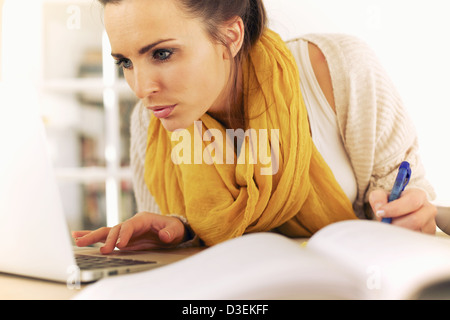 Beautiful college student busy browing the internet and writing down information Stock Photo