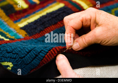 Hands work a hook in hug hooking craft. Stock Photo