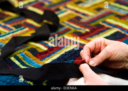 Hands work a hook in hug hooking craft. Stock Photo