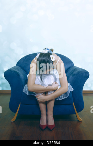 a woman in a white dress is sitting on a blue armchair