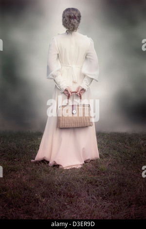 a woman in a victorian dress with a handbag made of bast Stock Photo