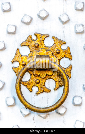 An ornate golden ring knocker on a bright white painted wooden door. Stock Photo