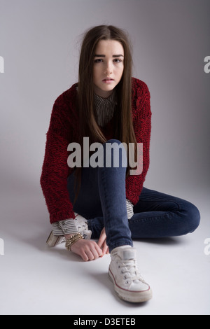 Portrait of a 15 year old girl sitting on a studio floor. Stock Photo