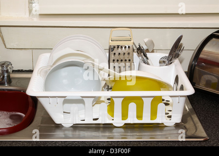 Dishes in plastic drying rack on draining board Stock Photo
