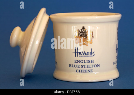 pot for Harrods Knightsbridge English blue Stilton cheese with lid off and resting by side isolated on blue background Stock Photo