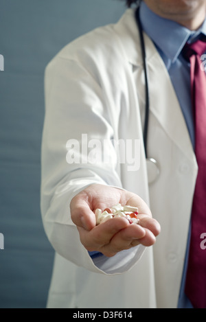 Male doctor with hand full of pills, close up image with shallow depth of filed with focus on hand with cure. Stock Photo