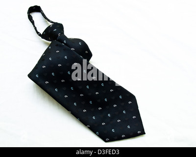 A rolled up dotted black tie isolated on white background. Stock Photo