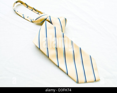 A rolled up striped yellow and blue tie isolated on white background. Stock Photo