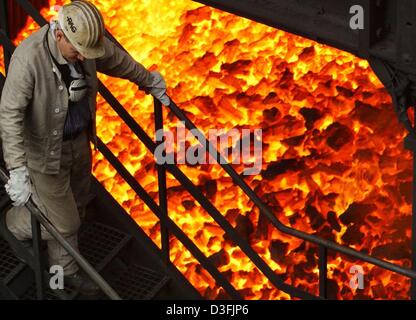 (dpa) - A worker passes a waggon filled with red hot coke in the coking plant Prosper in Bottrop, Germany, 5 July 2003. The second largest of the five remaining cokeries in Germany produces around two million tons of coke. The cokery celebrates its 75th anniversary this year. Stock Photo