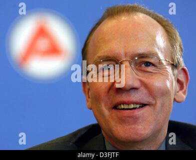 (dpa) - Florian Gerster, Chairman of the Federal Employment Office, smiles in front of the Arbeitsamt (job centre) logo as he presents the current statistics for the German labour market in Nuremberg, Germany, 8 July 2003. German unemployment has fallen for the fourth month in a row, fuelling government hopes that the country could be over the worst of its economic woes. The fall w Stock Photo