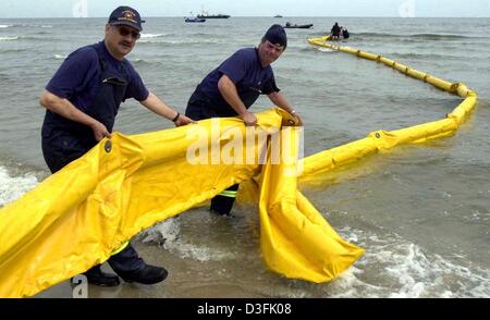 (dpa) - Firemen lay out an oil barrier during an emergency exercise for a staged oil disaster on the Baltic Sea coast of the Island Usedom near Ahlbeck, Germany, 18 June 2003. In the joint exercise of German and Polish rescue workers the helpers learned how to haul and secure the damaged ships and how to pump up the oil slick. Stock Photo