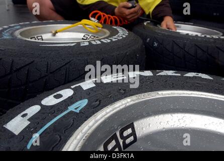 (dpa) - Rain drops are seen on rain tyres while a mechanic checks the tyre pressure in the pits at the racetrack in Magny-Cours, France, 3 July 2003. The Formula One Grand Prix of France will take place on Sunday 6 July in Magny-Cours. Stock Photo
