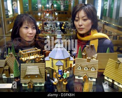 (dpa) - Two young Japanese women look at a village made of typical wooden turnery figures at the toy museum in Seiffen, eastern Germany, 16 December 2004. More and more tourists from the Far East are coming to the region of the Erz Mountains to buy the famous turnery figures. Especially incense holders, nutcrackers, pyramids and wooden toys are well-known far beyond Germany. Stock Photo