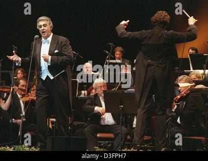 (dpa files) - Spanish tenor Placido Domingo (L) sings, accompanied by the Nordwestdeutschen Philharmonie (Northwest German Philharmonic O rchestra) and conducted by Karl Sollak , at a concert in Halle, Germany, 14 July 2001. Placido Domingo's family emigrated in 1949 to Mexico where he grew up and studied voice, piano and conducting at the Mexico City Conservatory. He made his oper Stock Photo