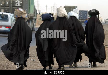 (dpa) - A group of Iraqi women carry groceries and other food in bags on their head in Baghdad, Iraq, 8 May 2003.The security has been significantly improved after a period of lawlessness and looting. Even the hospital services seem to be operational again. However, there is still a lack of essential, necessary medicine. The power grid is working at 40 to 50 percent and tab water i Stock Photo