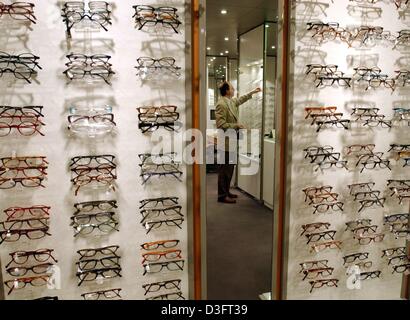 (dpa) - The reflection in the mirror shows an employee sorting glass frames in a display case in the local branch of Fielmann AG, the optician and eyeglasses corporation in Schwerin, Germany,  27 March 2003. Last year, around 55 percent of glasses were ordered directly from the optician. This highlights the continuous trend of customers to purchase their glasses without prescriptio Stock Photo