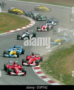 (dpa) - German Ferrari driver world champion Michael Schumacher (L) and his teammate Brazilian Rubens Barrichello lead the pack into the first curve of the Spanish Grand Prix on the Circuit de Catalunya in Barcelona, 4 May 2003. Michael Schumacher came in first, Fernando Alonso (Renault, behind the two Ferraris) finishes second, and Barrichello third. Stock Photo