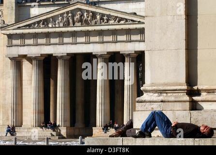 (dpa) - A man takes an early sun bath in front of the sculpture gallery (Glyptothek) at the Koenigsplatz (king's square) in Munich, 26 February 2003. Stock Photo