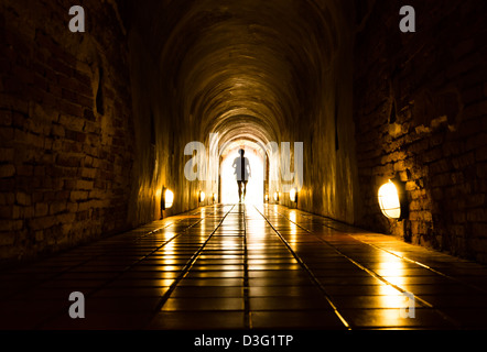 silhouette of human in old brick tunnel light at end of tunnel Stock Photo