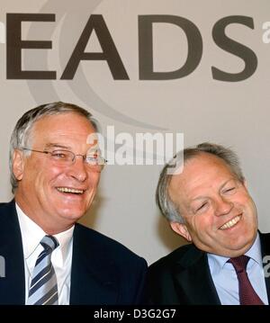 (dpa) - Philippe Camus (R) and Rainer Hertrich, heads of the European Aeronautic Defence and Space Company (EADS), laugh under the company logo in Munich, Germany, 10 March 2003. After last year's revenue losses, EADS will keep facing the crisis by cutting more jobs. Stock Photo