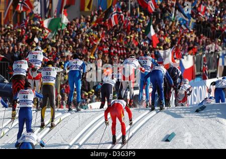 (dpa) - A group of skiers struggles uphill after the starting shot at the Nordic Skiing World Championship in cross-country skiing in Val di Fiemme, Italy, 22 February 2003. The competition is also called the skiathlon which involves the use of two different skiing techniques. For the first 10 kilometers athletes have to use the classical style and for the second 10 kilometers the  Stock Photo